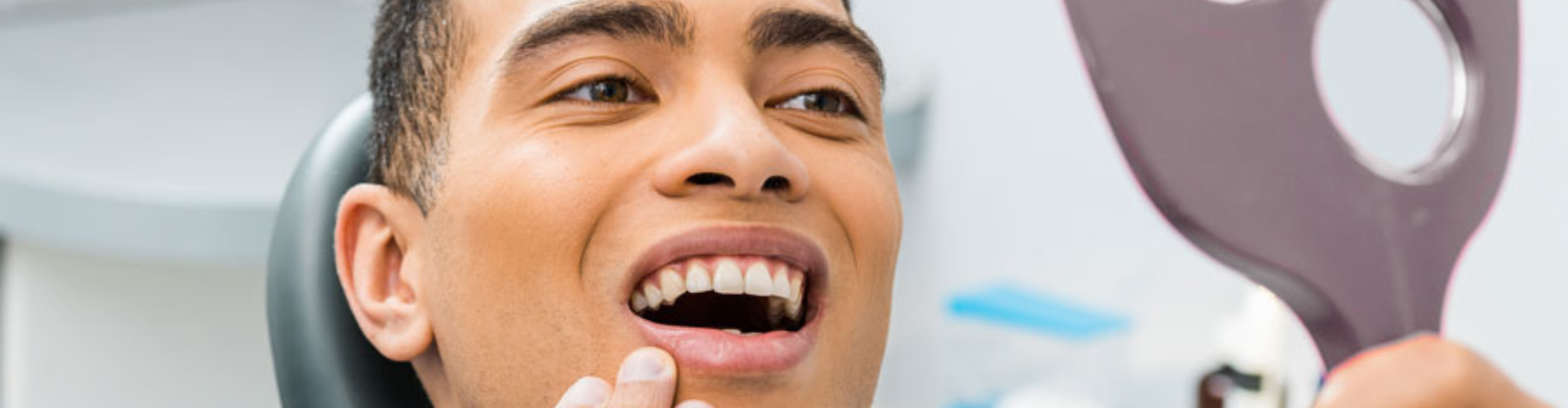 Man touching his chin and looking into a handheld mirror.